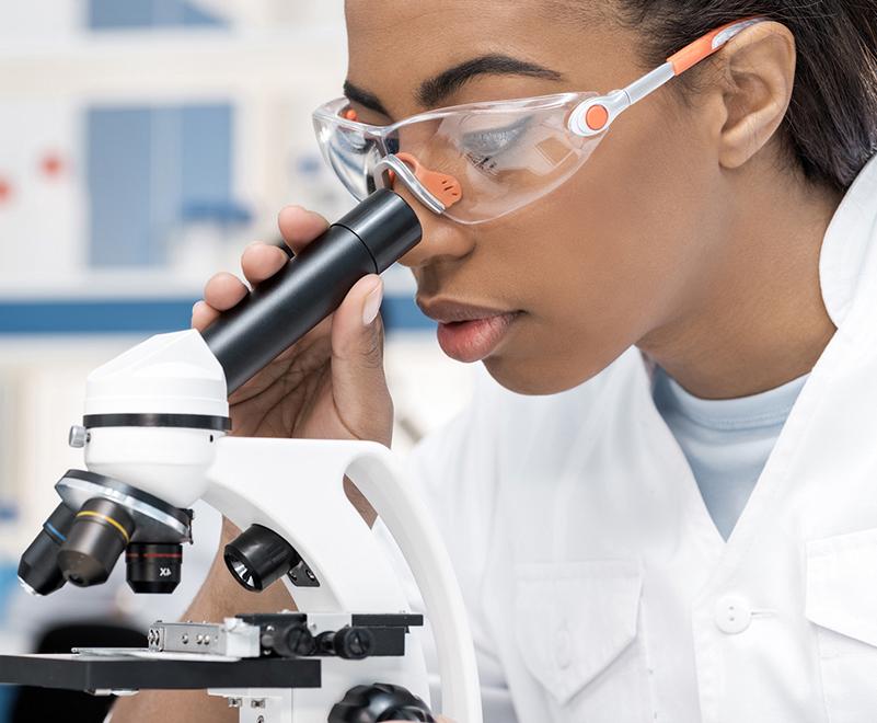 戴着护目镜的女人在看显微镜