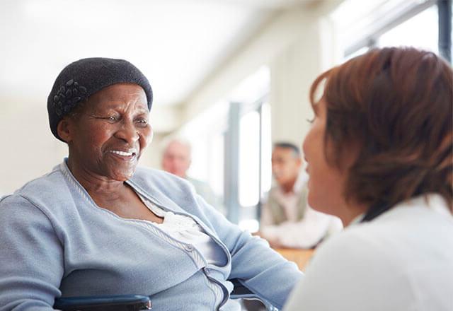 patient in a chair smiling at a caregiver